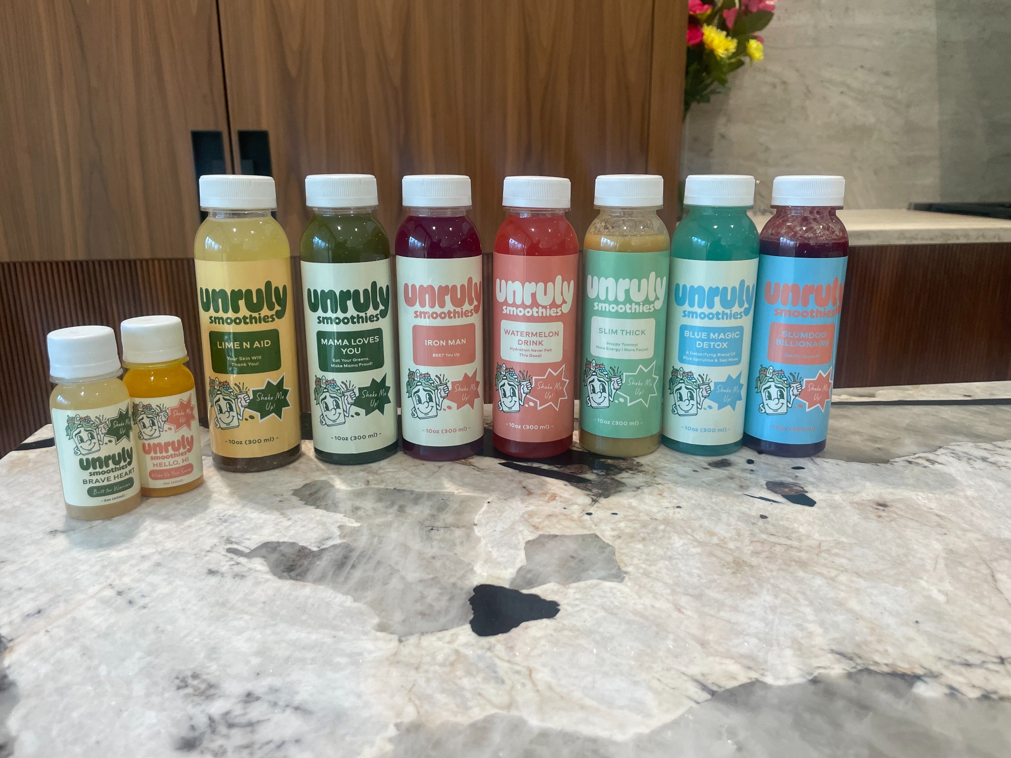 Nine real Unruly Smoothies juices and shots lined up with every full label and logo visible